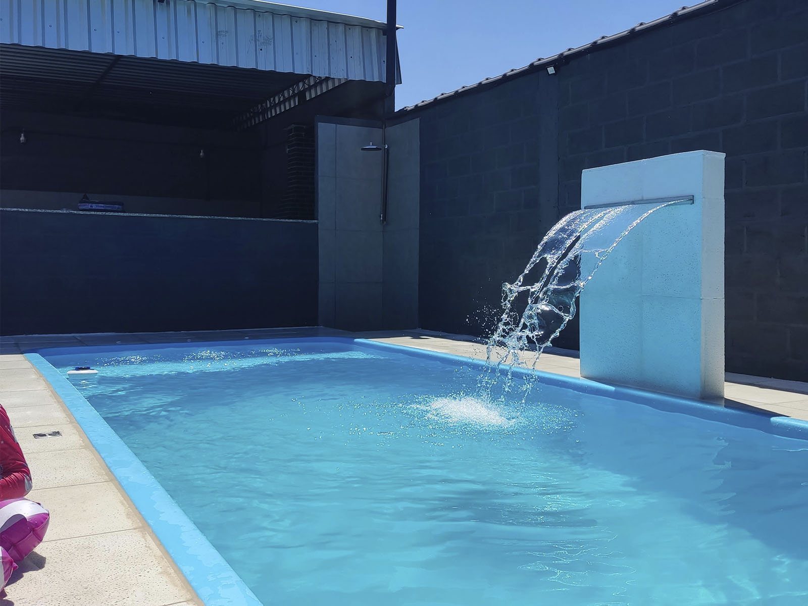 Piscina grande com cascata e deck, vista de dia